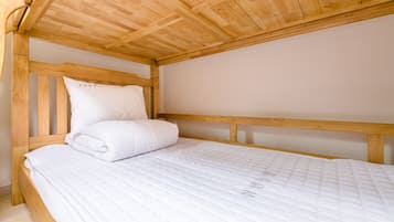 A single bed with a wooden headboard and white bedding in a room with wooden ceiling beams.