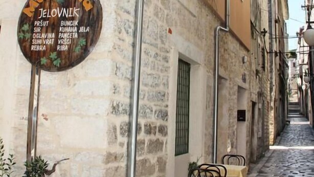 Un vicolo stretto con posti a sedere all'aperto e una targa che elenca attività commerciali locali.