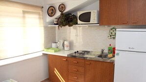 Una cucina con mobili in legno, un forno a microonde, un frigorifero e una finestra con persiane.