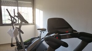 A gym with stationary bikes, a treadmill, and a window providing natural light. - Residencia La Ribera (Logroño)