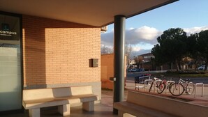 A covered outdoor area with a brick wall, a bench, and a bicycle rack. - Residencia La Ribera (Logroño)