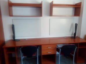 A wooden desk with two chairs, a whiteboard, and a computer monitor. - Residencia La Ribera (Logroño)