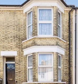 A corner bay window with white frames and a brick facade.