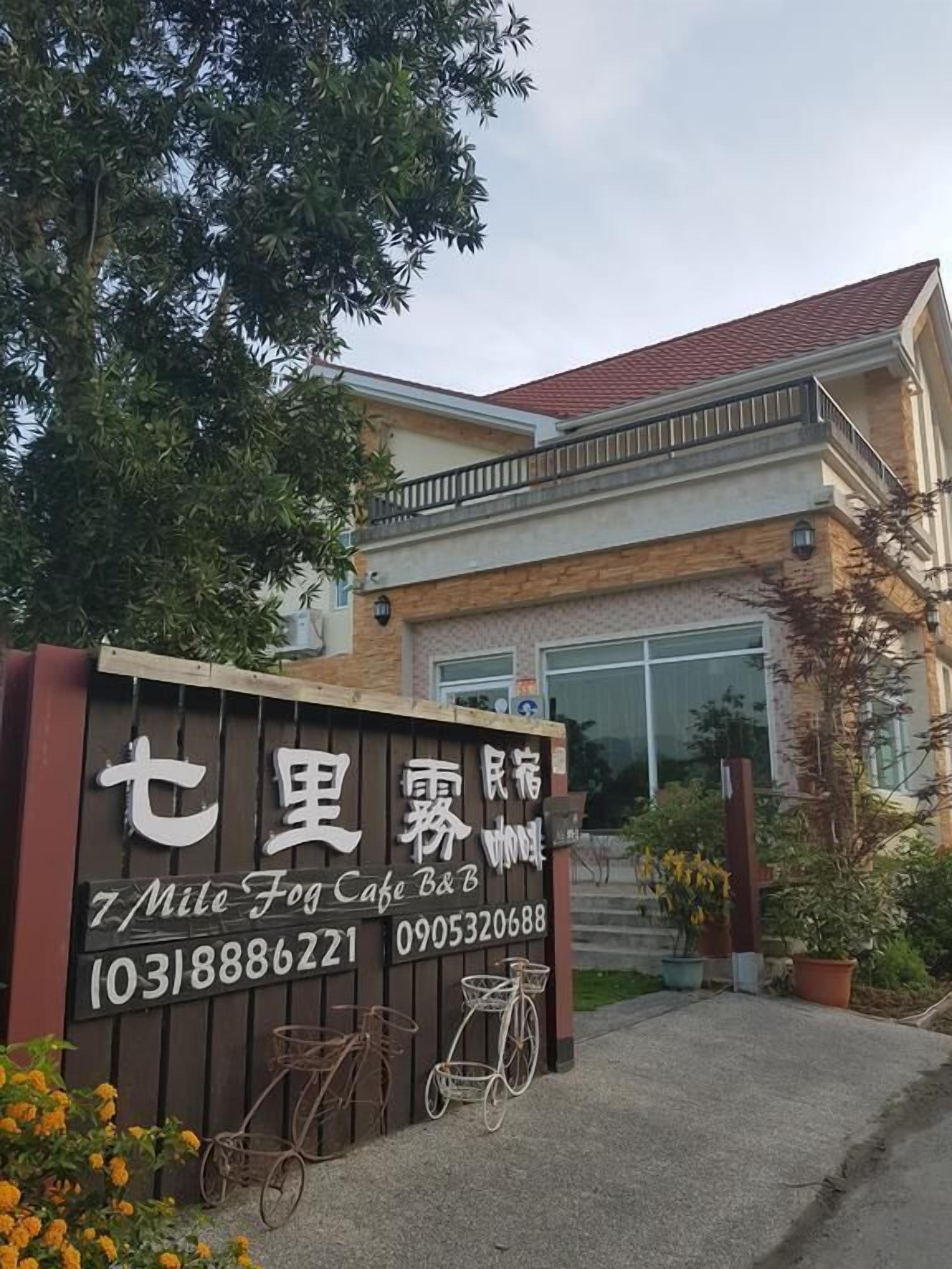 Un bâtiment avec une enseigne indiquant « 7 Mile Fog Cafe B&B » et un numéro de téléphone. On peut voir des vélos garés devant.