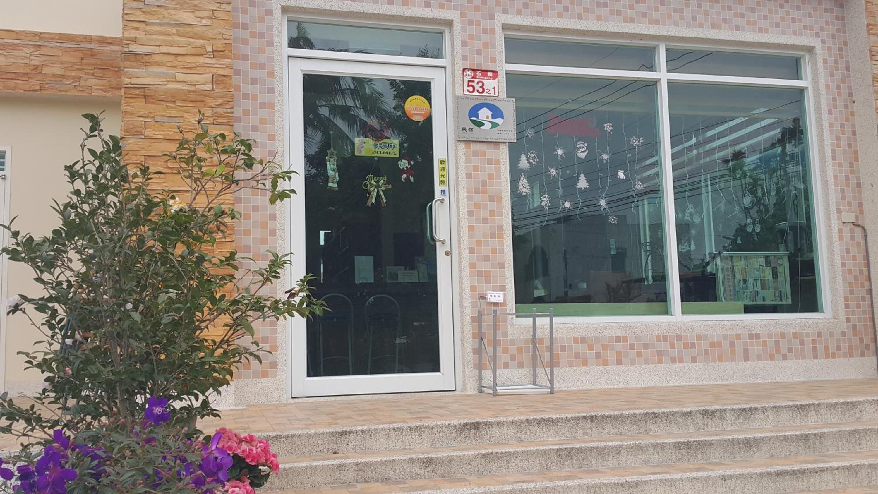 A building with a tiled facade, a large window with a sticker, and a door with a sign.