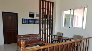 A living room with a brown leather sofa, wooden coffee table, and a wooden railing. - 7 Milefog B&B (Yuli)