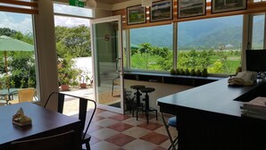 A restaurant with a view of the mountains, a glass door leading outside, and a table with a tissue box. - 7 Milefog B&B (Yuli)