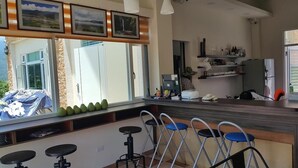 A modern kitchen with a bar area, large windows, and a view of the outdoors. - 7 Milefog B&B (Yuli)