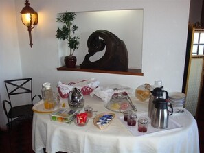 Une table de petit-déjeuner avec divers aliments, une cafetière et un élément décoratif mural.