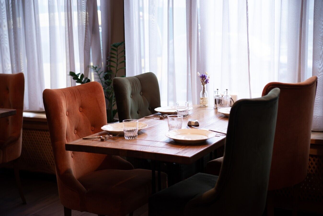 A dining area with a wooden table set for four, surrounded by upholstered chairs.