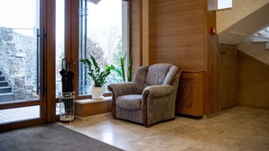 Una habitación con un ventanal grande, una silla, una planta en maceta y una escalera.