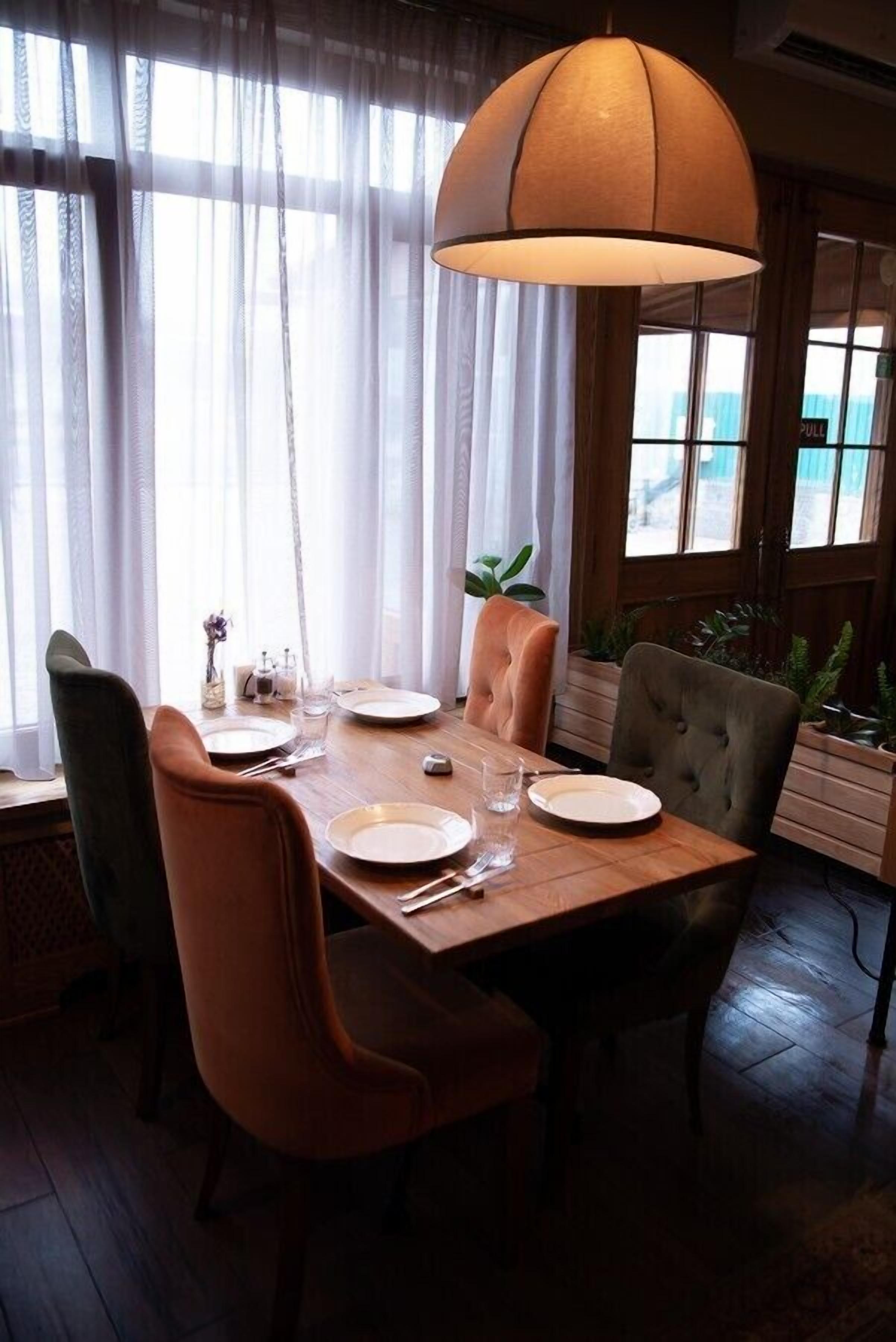 A dining area with a wooden table set for four, surrounded by upholstered chairs.