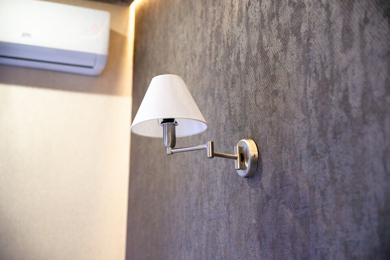 A wall-mounted light fixture with a white lampshade and a metallic base.