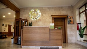 Un mostrador de recepción con detalles de madera, un fondo de pared de piedra y un cuadro colgado sobre la puerta.