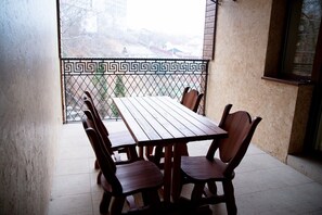 Una mesa de madera con seis sillas en un balcón con barandilla de metal.