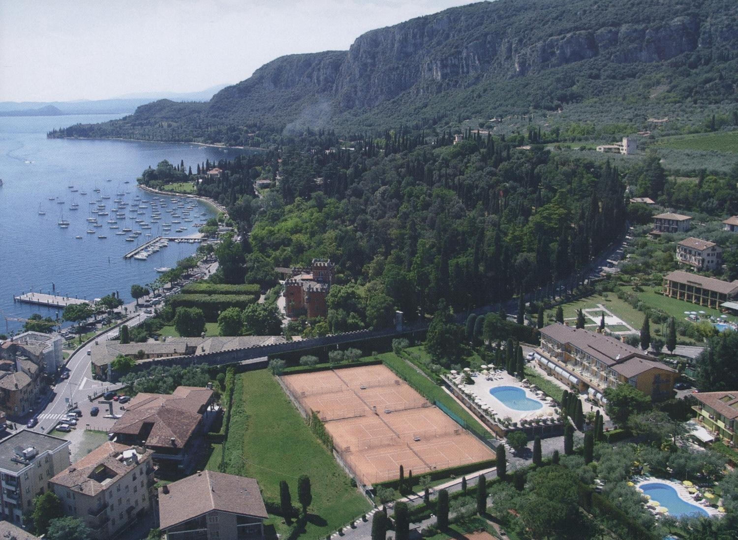 A coastal town with a marina, a large open tennis court, and a swimming pool.