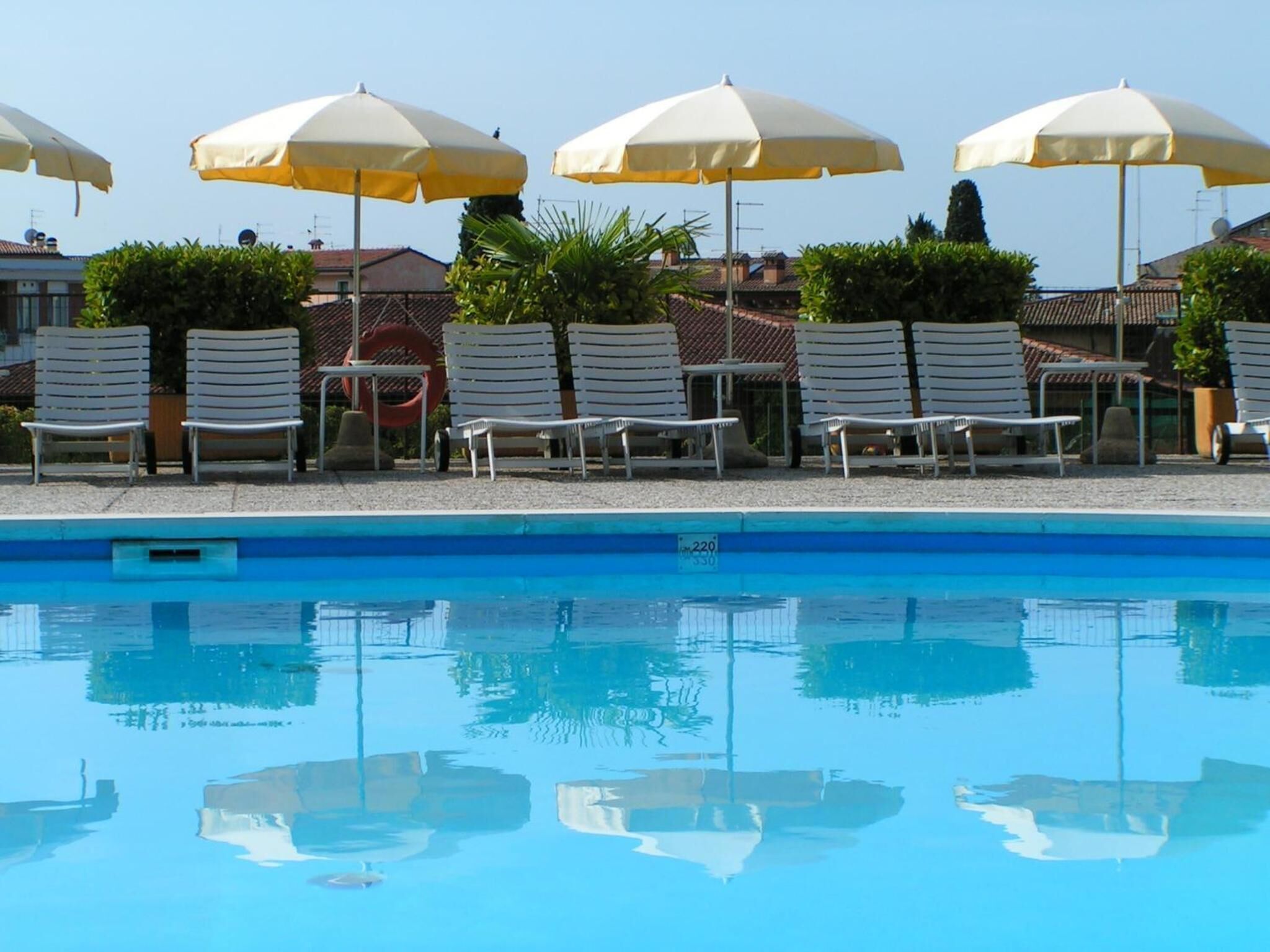 Una piscina con lettini bianchi e ombrelloni gialli.