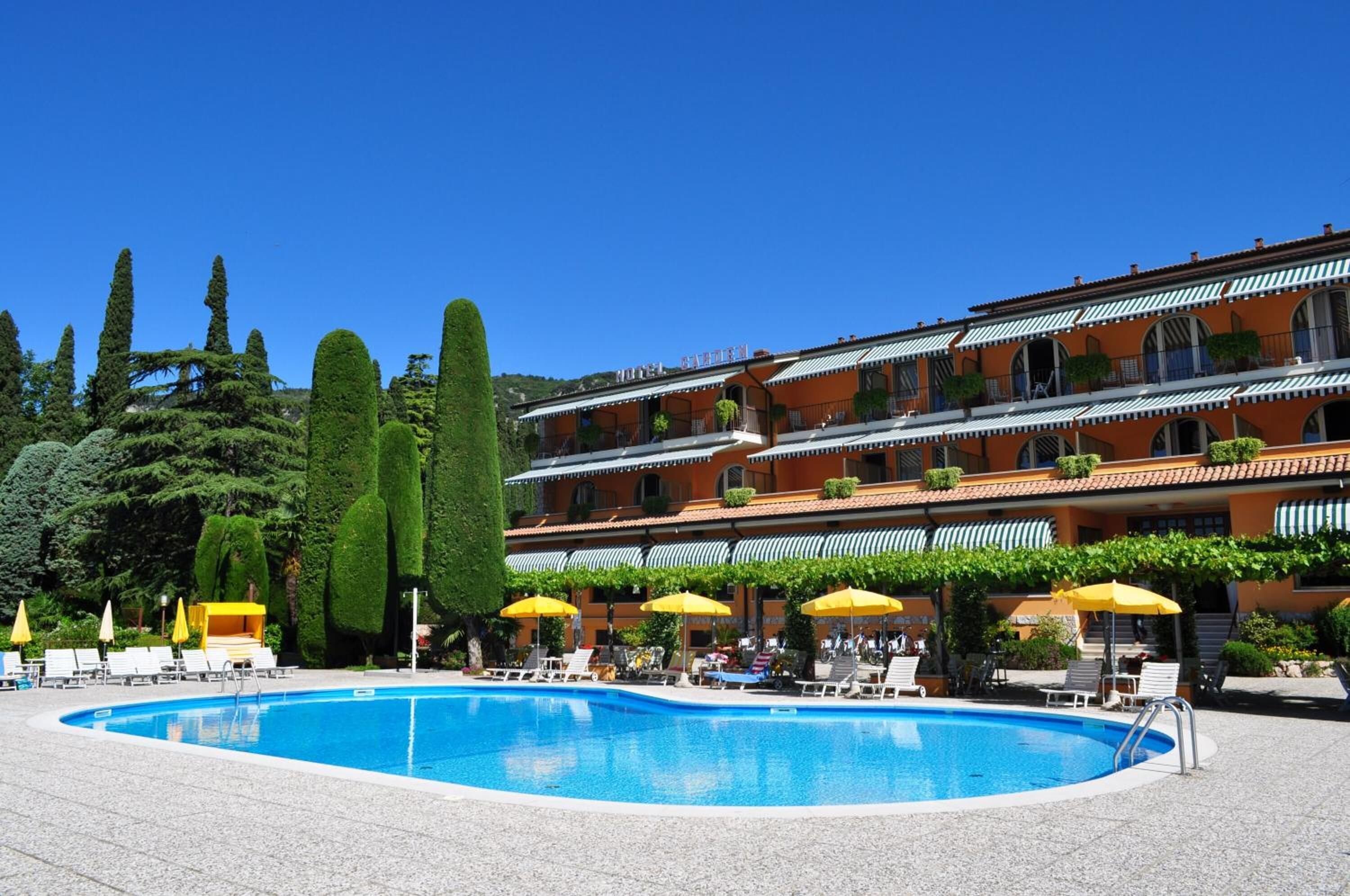 Un hotel con piscina, diversi balconi e zone relax all'aperto.