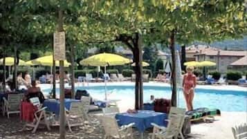 A poolside area with lounge chairs, umbrellas, and a swimming pool.
