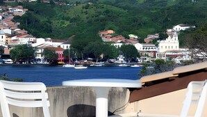 Une vue sur la mer, avec une table et des chaises donnant sur un port où se trouvent des bateaux et des bâtiments.