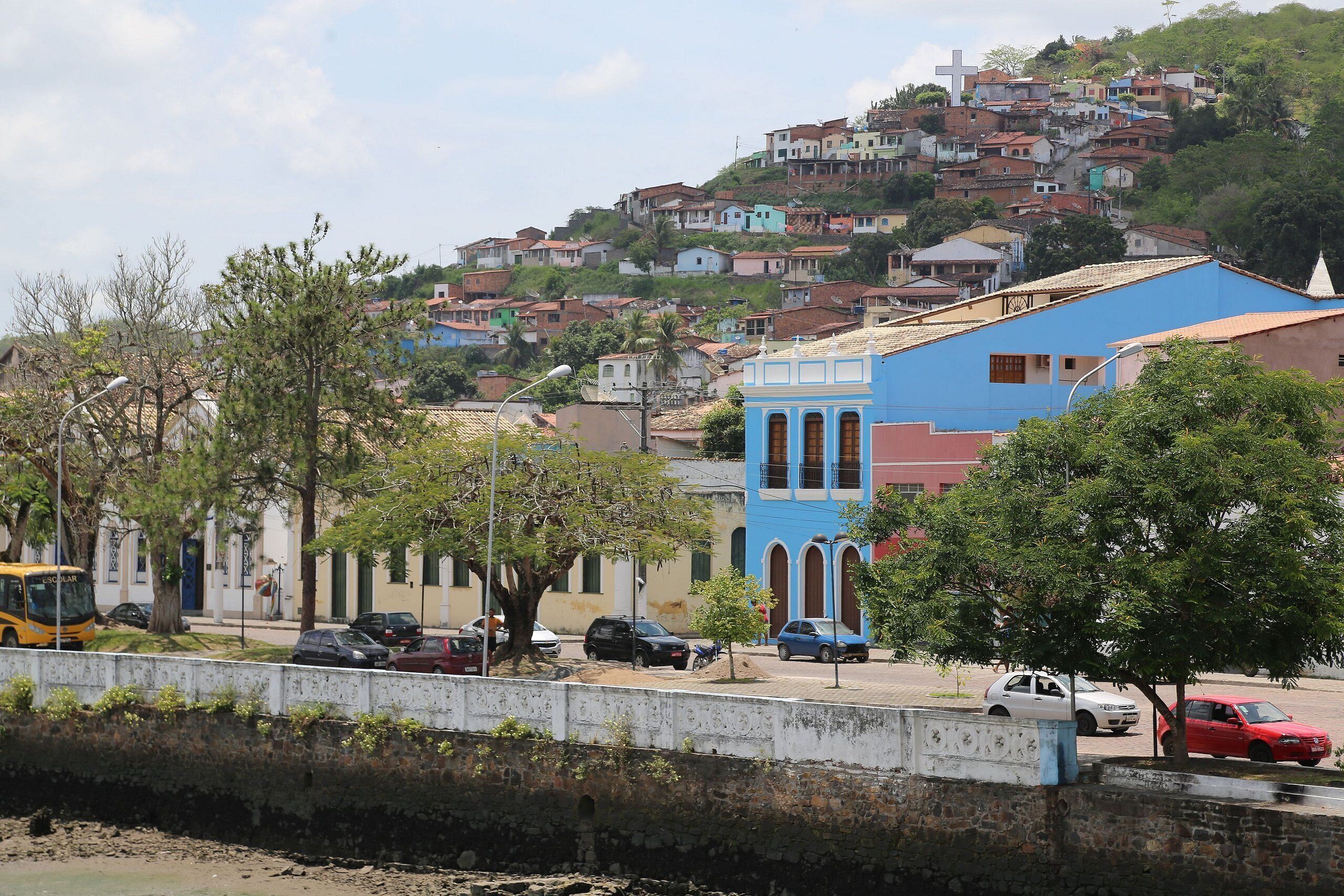 A hillside residential area with colorful houses, a blue building with arched windows, and a white building with a cross.