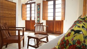 Une pièce de style traditionnel, dotée de meubles en bois, d’une cloison en osier et de grandes fenêtres avec des volets en bois.