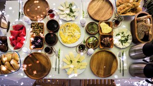 Una mesa dispuesta con diversos platos, incluyendo pan, queso y una tortilla grande, sugiriendo un ambiente para comer.