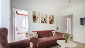 Un salón con un sofá marrón, una mesa de centro redonda y tres obras de arte abstracto en la pared.