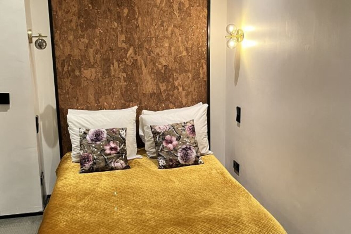 A room with a bed, two white pillows, and a floral-patterned pillow.