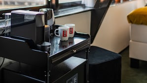 A room with a window, a coffee machine, and two cups on a tray.