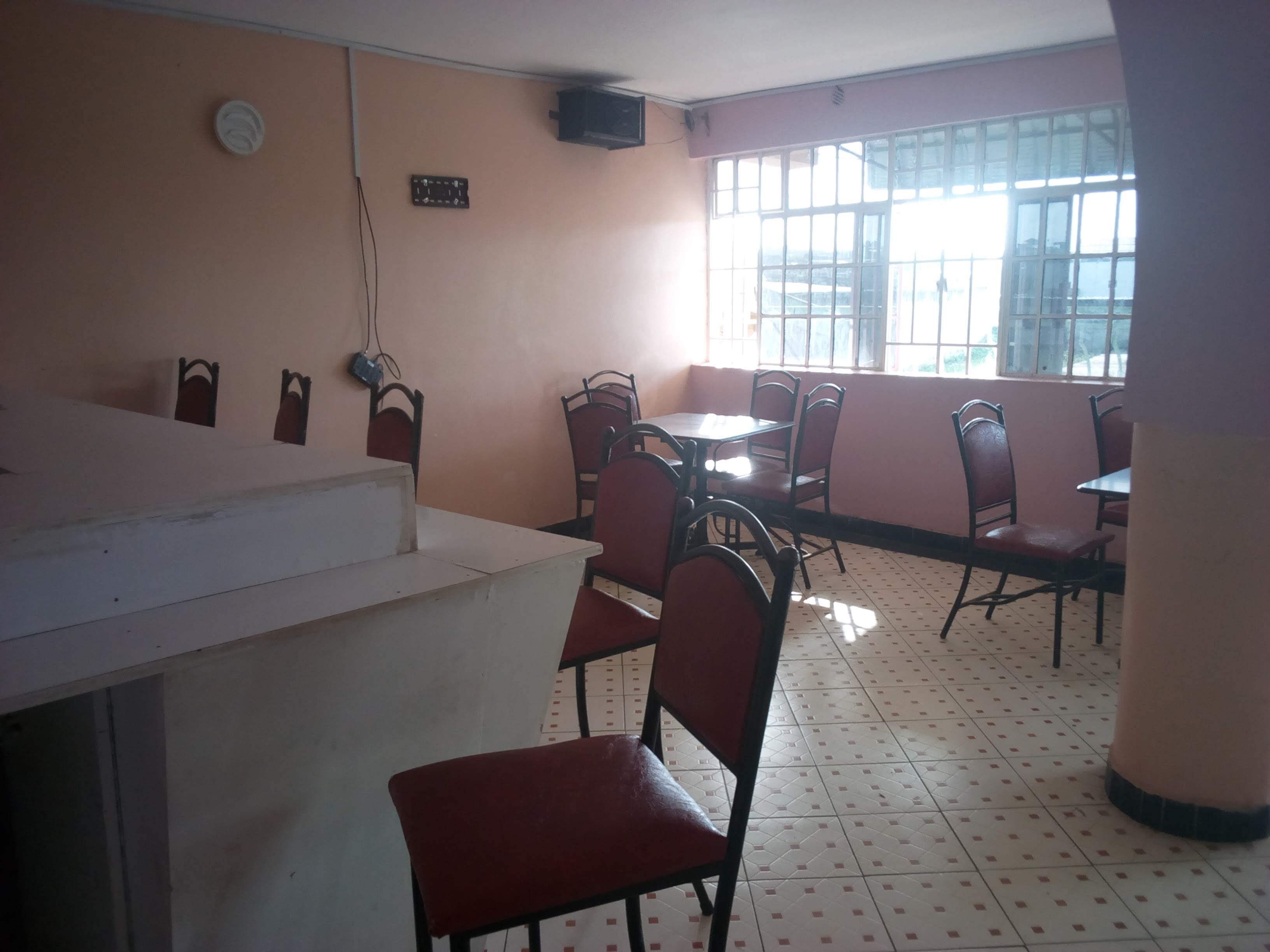 A restaurant interior with a counter, multiple tables, and chairs.