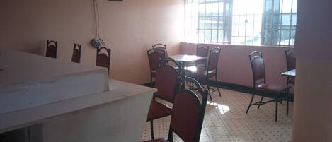 A restaurant interior with a counter, multiple tables, and chairs.