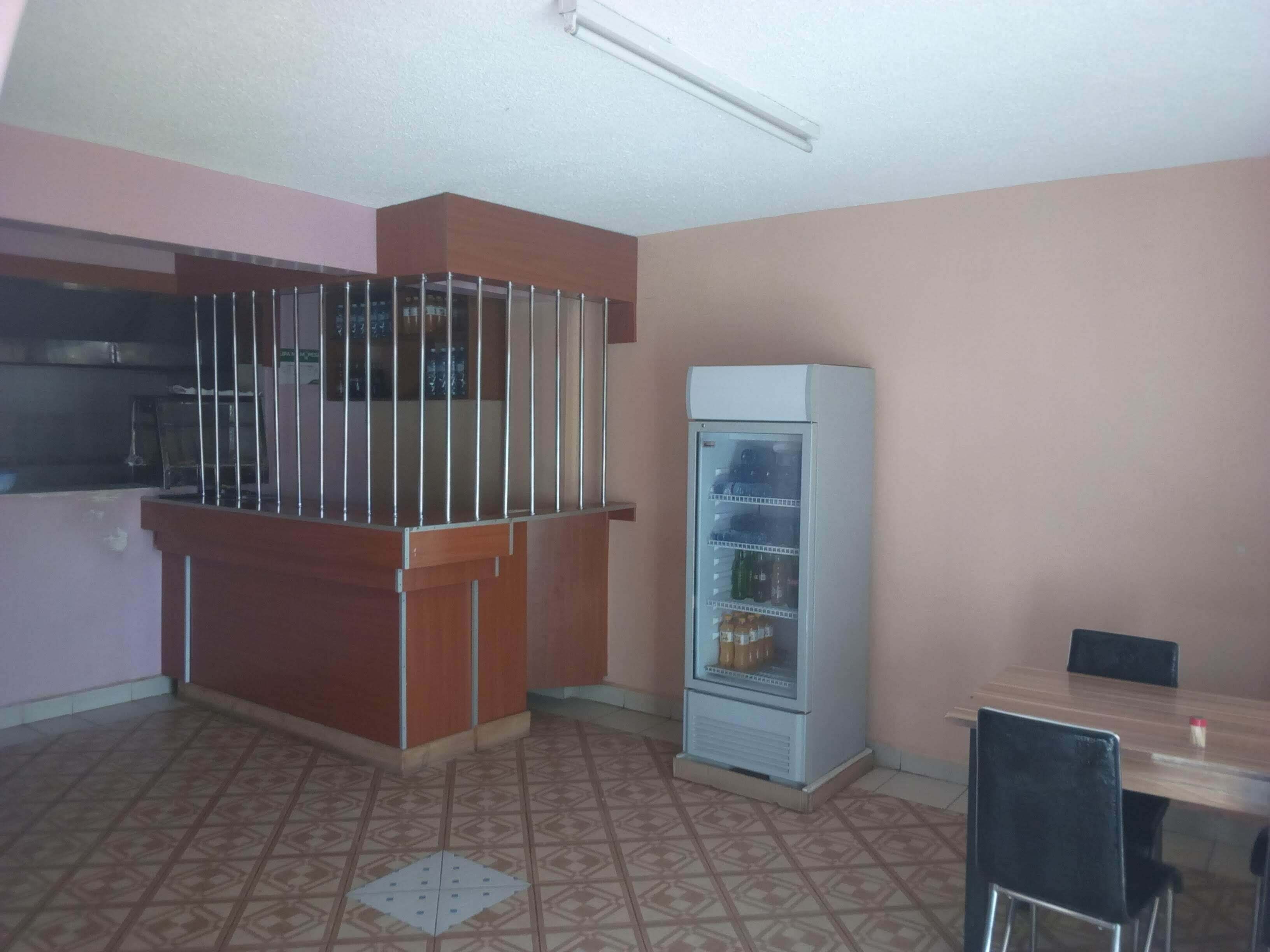 A small kitchenette with a refrigerator, a sink, and a bar counter.