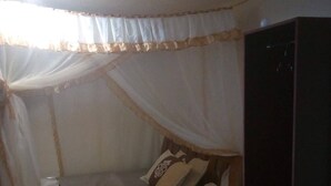 Ein Zimmer mit einem Bett unter einem Baldachin, einem Kleiderschrank und einem grünen Teppich.