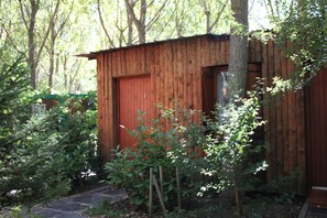 A wooden cabin with a red door, surrounded by dense greenery and trees. - Pirineos Cien Lagos (Esterri D'Aneu)