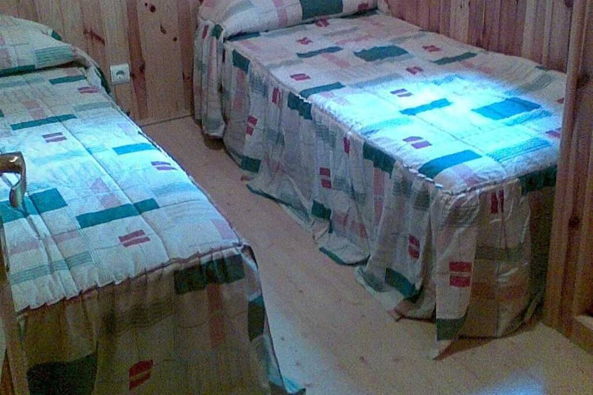 Une chambre avec deux lits simples, des murs en bois et une fenêtre.