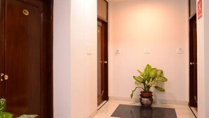 Un couloir avec une porte en bois portant le numéro « 103 » et une plante en pot placée au centre.