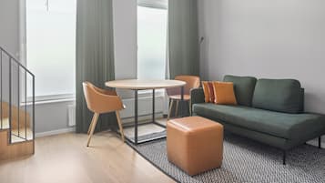 A modern living room with a round table, two chairs, a sofa, and a small ottoman.