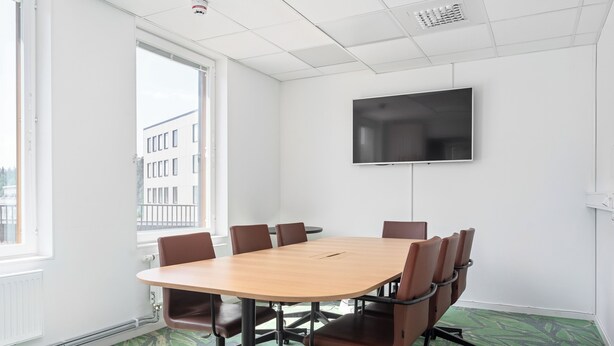 A conference room with a large table, six chairs, a flat-screen TV, and a window with a view of buildings. - Part-Time Home Täby (Taby)