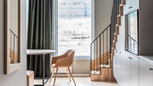 A modern interior with a staircase, a view of a snowy landscape, a wooden chair, and a table. - Part-Time Home Täby (Taby)
