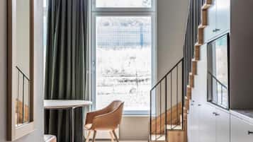 Een modern interieur met een trap, een raam met gordijnen en een houten stoel.