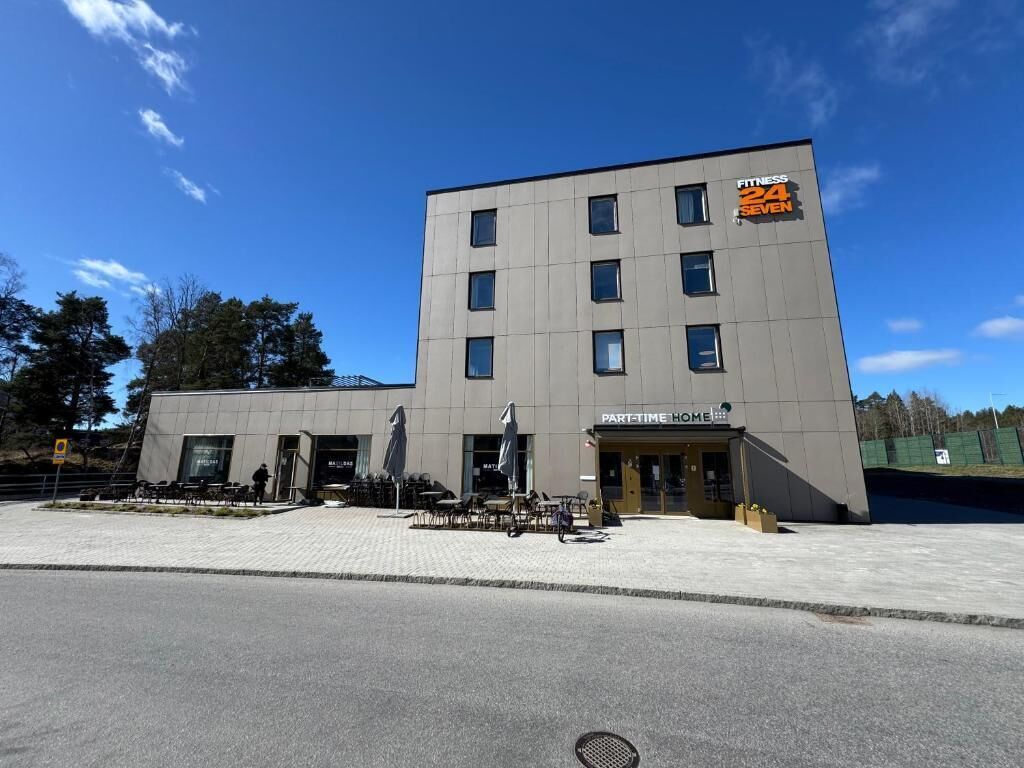Ein modernes Gebäude mit einem Schild für 'Fitness 24 SEVEN' und 'PARTTIME HOME'.