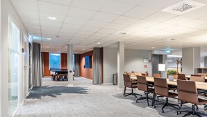 A modern conference room with a long table and chairs, a carpeted floor, and a view of a forest through a window. - Part-Time Home Täby (Taby)
