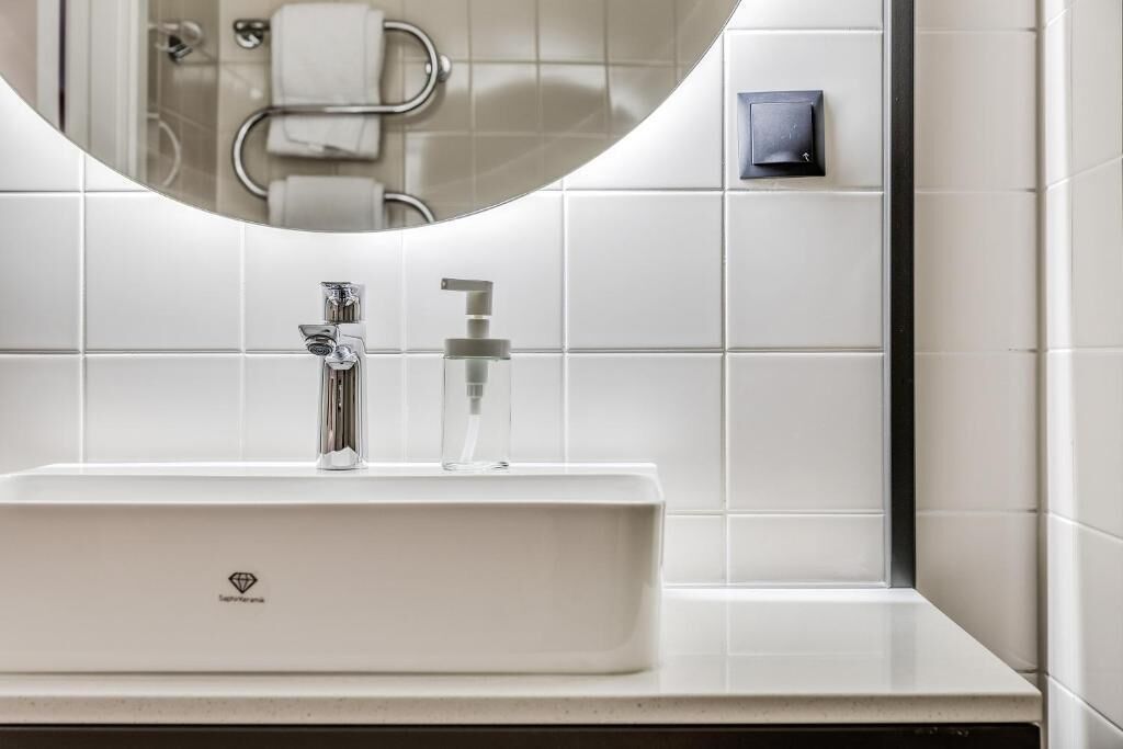 Une salle de bain moderne avec un lavabo blanc, un miroir et un porte-serviettes.