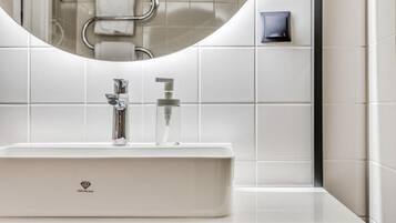 Une salle de bain moderne avec un lavabo blanc, un miroir et un porte-serviettes.