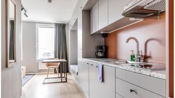 Cocina compacta con cafetera, lavamanos y armarios.