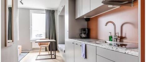 A compact kitchen with a coffee maker, sink, and cabinets.