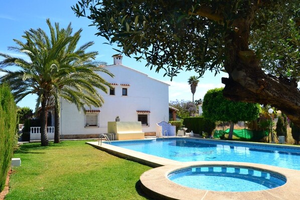Relax by the serene pool surrounded by lush greenery and palm trees.