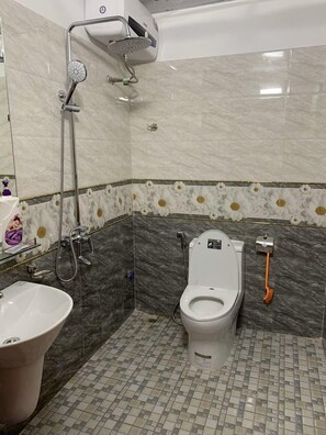 Une salle de bain équipée de toilettes, d’un bidet et d’un lavabo.