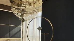 Une cuisine moderne avec un plan de travail noir, un luminaire décoratif en métal et un vase rempli de fleurs.